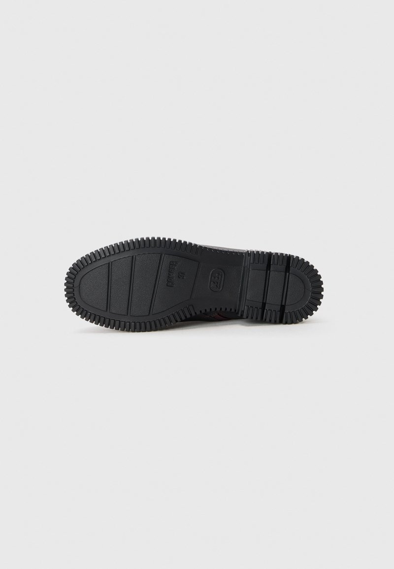 Suola di scarpa in gomma nera con un motivo di grip texturizzato, caratterizzata da creste e sezioni rialzate per una migliore aderenza. Design robusto e flessibile.