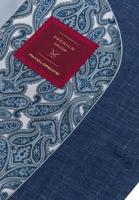 Ciemnoniebieska tkanina ozdobiona wzorem paisley w odcieniach niebieskiego i białego, z burgundową metką z napisem "Premium Selection" wszytą na niej.
