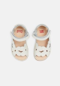 Valkoiset nahkasandaalit kukkakuvioisilla leikkauksilla, säädettävillä remmeillä ja beigenvärisellä pohjallisella, joissa on punaiset "CAMPER"- ja "TWINS"-yrityksen logo.