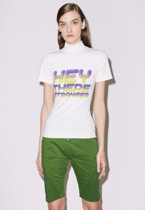 White short-sleeve t-shirt featuring purple and yellow block letters reading "HEY THERE STRANGER." Paired with green shorts, textured accents visible.