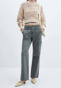Maglione corto lavorato a maglia di colore rosa chiaro con fili multicolori, abbinato a pantaloni cargo grigi larghi con tasche laterali e gamba dritta.