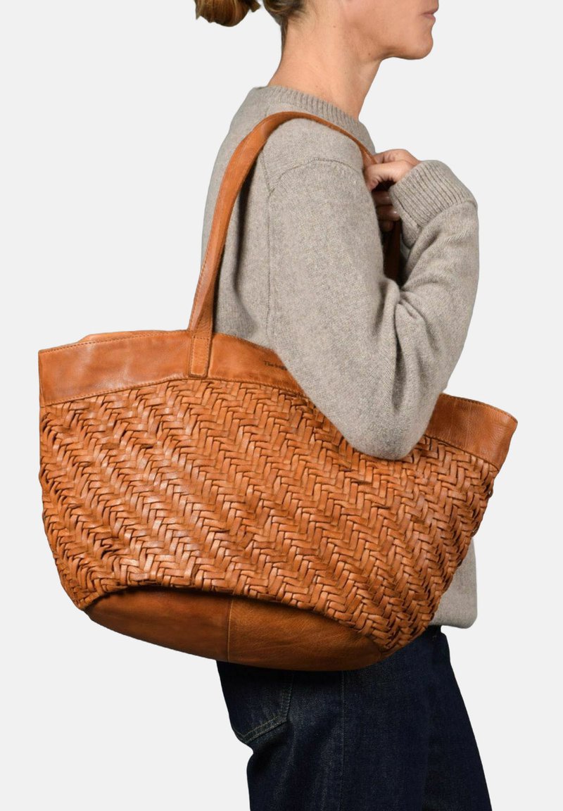 Geweven tan leren tote bag met een gladde leren basis, stevige schouderbanden en een gestructureerd patroon op het lichaam.