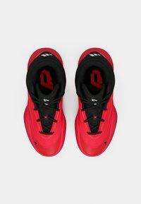 Un paio di scarpe da ginnastica rosse e nere con lacci neri posizionate affiancate su uno sfondo bianco, viste dall'alto.