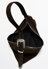 Brown suede bag with a zipper closure, wide opening, and contrasting black interior. Features a long, flat strap with a silver buckle.