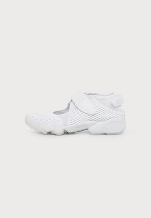 Witte Nike Air schoen met mesh bovenwerk, verstelbare klittenbandsluiting bovenop en bij de hiel, en een gestructureerde zool voor grip.