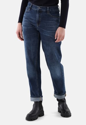 Jeans blu scuro con vestibilità comoda, orli risvoltati e tasche anteriori. Realizzati in denim con una leggera sfumatura e cuciture a contrasto. Abbinati a stivali neri.