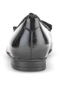 Zwarte gepatineerde leren dames ballerina met ronde hak en zichtbare stiksels aan de achterkant, weergegeven vanuit de achteraanzicht op een witte achtergrond.
