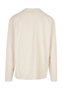 Langermet T-skjorte i off-white med rund hals og en myk, glatt tekstur. Enkelt design, ingen synlige mønstre eller detaljer.