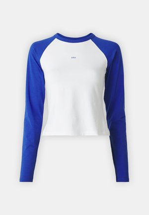 Balta palaidinė su ilgomis mėlynomis raglaniniu rankovėmis, apvalia iškirpte ir mažų mėlynų "JJXX" logotipu, kuris yra centriniame priekyje. Minkšta, elastinga medžiaga.