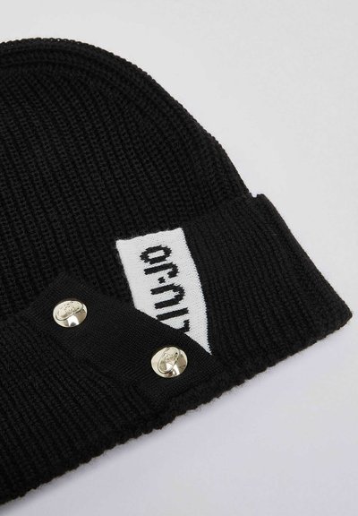 Bonnet en maille côtelée noire avec revers plié, comportant une étiquette tissée blanche avec texte noir et deux boutons-pression métalliques brillants sur le revers.
