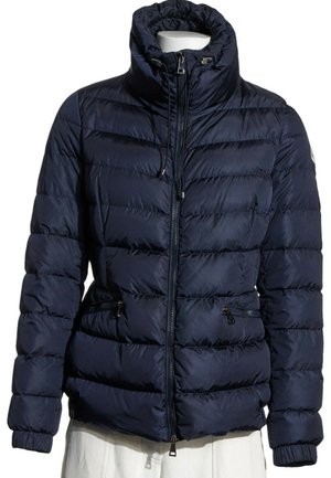 Chaqueta acolchada azul marino con cuello alto, cremallera frontal, cordón y bolsillos laterales con cremallera en un maniquí blanco.