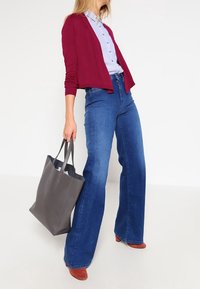 Maroon cardigan, light blue button-up shirt, high-waisted flared jeans, red suede heels, and a gray leather tote bag.