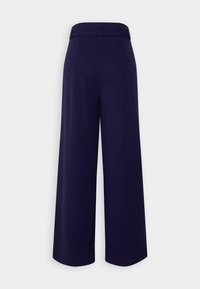 Pantalon large bleu marine avec taille haute et passants pour ceinture, vu de dos sur un fond clair uni.