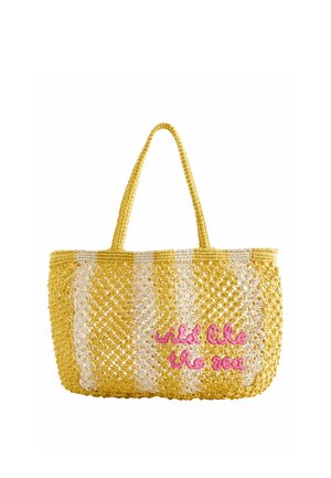Sac fourre-tout tissé à rayures jaunes et blanches avec deux poignées et texte rose brodé "wild like the sea" à l'avant.
