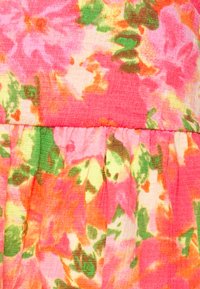 Tejido floral en tonos de rosa, naranja y verde. El material tiene un acabado texturizado con detalles fruncidos en la costura.