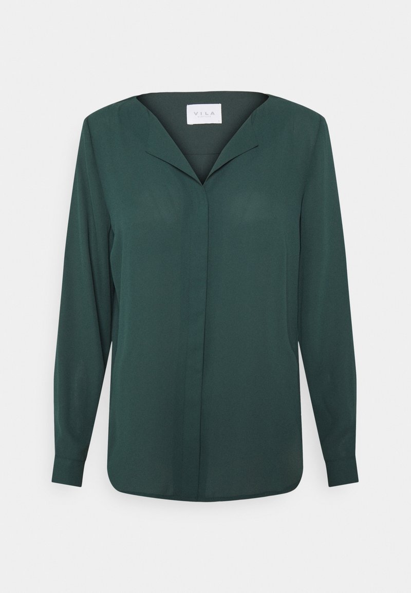 Blouse femme à manches longues de couleur vert foncé, col en V et boutons dissimulés à l'avant, présentée sur un fond clair uni.