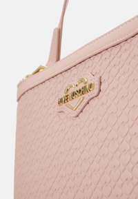 Pink textured handbag with a heart pattern, gold hardware, and the "Love Moschino" logo. Features a structured design and short handles.