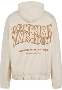 Cream hoodie with a drawstring hood, featuring brown block text on the back: "DROPSIZE" and "DROPSIZE CLUB / EST. 2020." Elastic hem.
