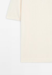 T-shirt beige clair à manches courtes en tissu doux, doté d'un col rond et d'un ourlet côtelé, avec une texture lisse et uniforme.