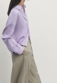 Lilac linen shirt with a collar and button front, paired with beige wide-leg trousers. The outfit features long sleeves with button cuffs.