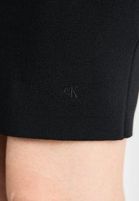 Črne prilegnjene kratke hlače iz teksturirane tkanine. Imate majhen, vtisnjen logotip na robu. Brezšiven dizajn, primeren za sproščeno nošenje.