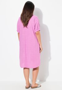 Rosa, knälång klänning i lätt tyg med korta puffärmar och en avslappnad passform, med en slät textur och rundad nederkant.