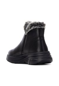 Botas de tobillo de cuero negro con trim de piel sintética en el cuello, suela texturizada y un diseño de bajo perfil para mayor comodidad.