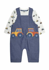 Denim-Latzhose mit zwei bunten Traktor-Applikationen auf der Vorderseite, kombiniert mit einem weißen Langarmshirt mit einem durchgehenden Traktor-Druck.