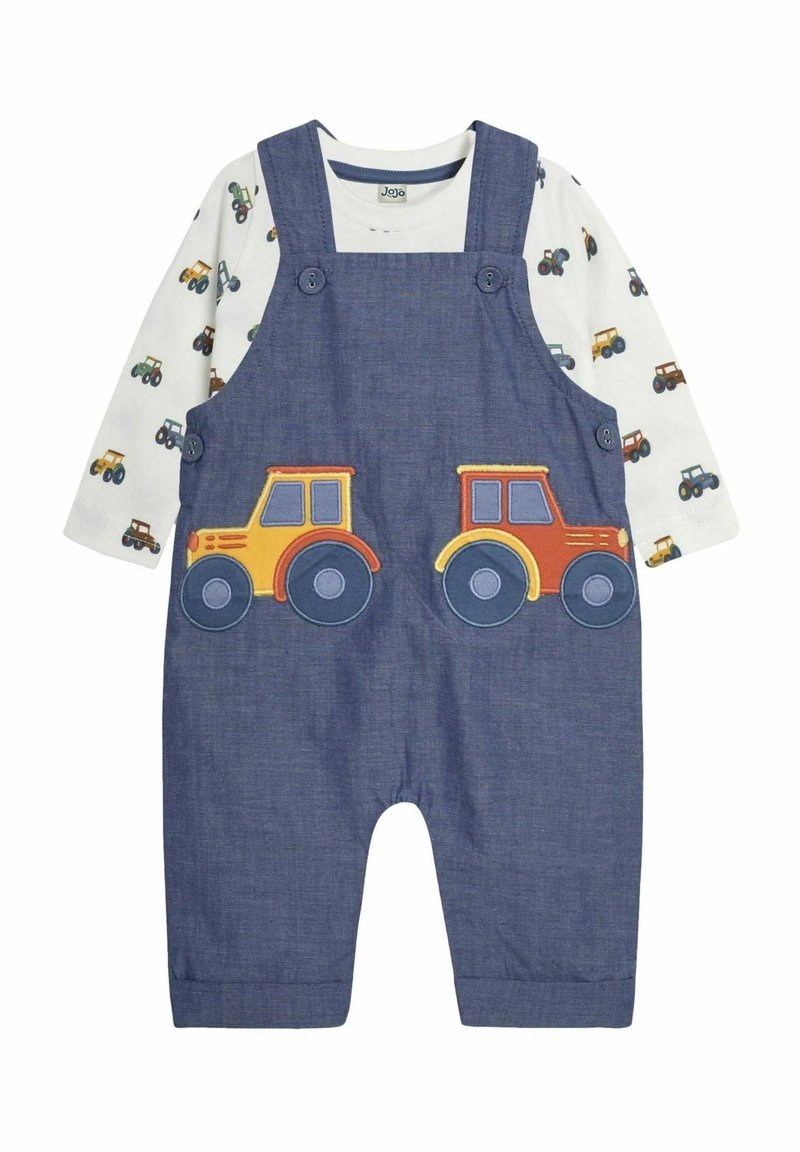 Denim-Latzhose mit zwei bunten Traktor-Applikationen auf der Vorderseite, kombiniert mit einem weißen Langarmshirt mit einem durchgehenden Traktor-Druck.