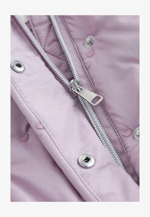 Heled lilla jope kangas, millel on tikitud tekstuur. Hõbedane tõmblukk ja metalldetailid; väiksed tikitud südame motiivid on nähtavad tõmbluku ja tihendite lähedal.