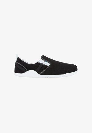 Zapatillas negras de tipo slip-on con parte superior de tejido texturizado, suela de goma blanca, paneles elásticos laterales y detalles de costura blanca en contraste.