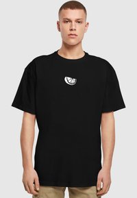 Tricou negru din bumbac, cu mâneci scurte, având o grafică albă a unei felii de citrice pe piept. Design simplu, cu o croială relaxată.