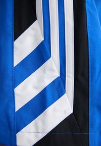 Gros plan de tissu bleu, blanc et noir avec des rayures diagonales et verticales blanches et bleues cousues.