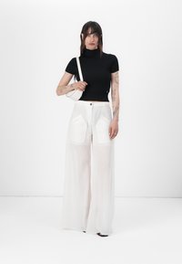 Svart ribbet turtleneck topp med korte ermer, sammen med løse, hvite vidbukser med to frontlommer. Minimalistisk håndveske inkludert.