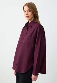 Bordeaux oversized shirt van katoen, met een knoopsluiting aan de voorkant, lange mouwen en een borstzak. Gladde textuur met een ontspannen pasvorm.