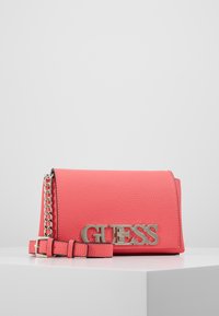 Borsa a tracolla rosa corallo con superficie testurizzata, logo in metallo argentato "GUESS", tracolla removibile e dettaglio a catena sulla tracolla.