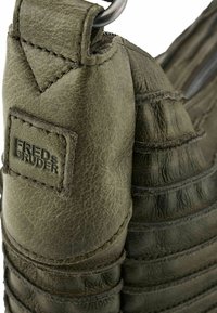 Borsa in pelle verniciata verde con texture e dettagli cuciti, dotata di una patch del marchio in evidenza, chiusura a zip e un design elegante e moderno.