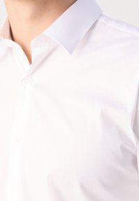 Witte katoenen blouse met een puntige kraag, met een gladde textuur, knoopsluiting en subtiele glans. Klassiek ontwerp voor zowel casual als formele gelegenheden.