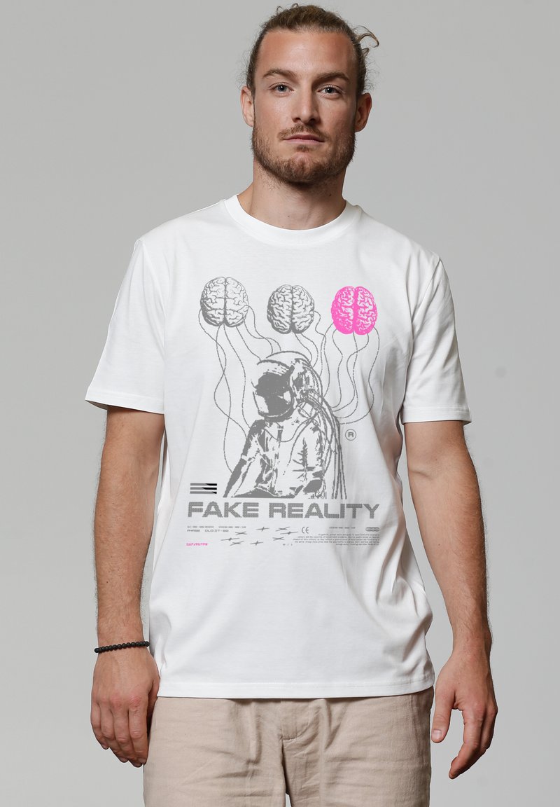 T-shirt en coton blanc avec un design graphique représentant un astronaute avec quatre cerveaux au-dessus, deux en gris et deux en rose, avec le texte "FAKE REALITY".