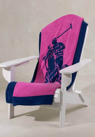 Λευκή ξύλινη καρέκλα με πετσέτα σε ναυτικό μπλε και ροζ χρώμα, που απεικονίζει έναν παίκτη πόλο πάνω σε άλογο, κρεμασμένη πάνω της.