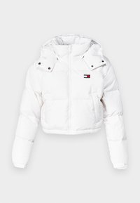 Vit kort vadderad jacka med huva, med dragkedja fram, tryckknappar och en liten logotyp i rött, vitt och blått på bröstet.