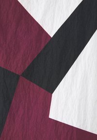 Formes géométriques superposées en rouge foncé, noir et blanc avec une texture froissée.