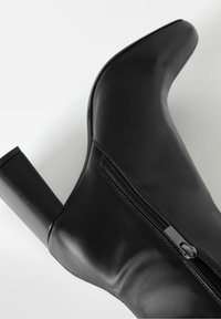 Schwarze Leder-High-Heel-Ankle-Boots mit spitzem Zehenbereich, seitlichem Reißverschluss und glatter Textur. Verfügt über einen stabilen Blockabsatz.