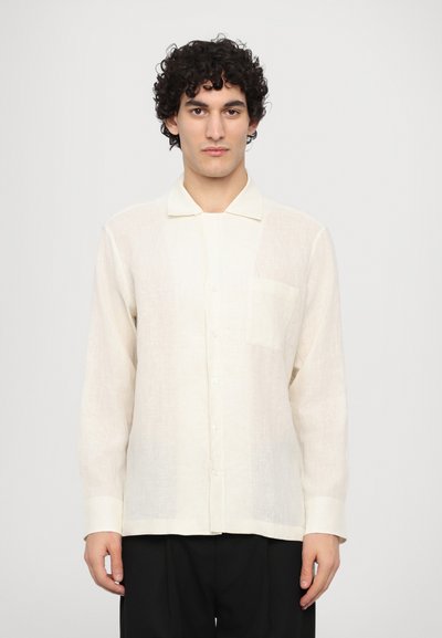 Camicia in lino di colore bianco sporco con colletto, maniche lunghe, chiusura con bottoni e una tasca sul petto. Tessuto testurizzato con una vestibilità rilassata.