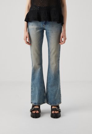 Lyseblå flagrende jeans med en falmet vask. Brukt med svarte chunky plattform sandaler med nagler. Krokheklede svarte topper med volangkant.