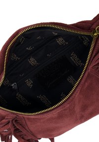 Bordeauxrode suède tas binnenkant met een zwarte stoffen voering, goudkleurige "Venezia" branding en een vak met rits voor organisatie.