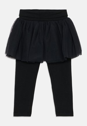Leggings neri con sovrapposizione di gonna in tulle a strati. Caratterizzati da una fascia larga e morbida in vita. Il tulle strutturato aggiunge dimensione e volume al design.