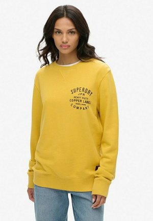 Gelbes Sweatshirt mit Rundhalsausschnitt, gerippten Bündchen und Saum. Auf der Vorderseite befindet sich schwarzer Markenaufschrift in einem geschwungenen Design. Lässige Passform.