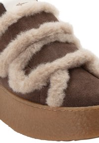 Gros plan d'une chaussure en daim marron avec une épaisse bordure beige duveteuse sur le dessus et une semelle en caoutchouc texturée.