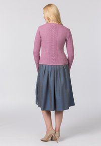 Rosa Strickpullover mit strukturierten Details entlang des Rückens, kombiniert mit einem grauen Rock. Das Outfit wird mit beigen High Heels abgerundet.